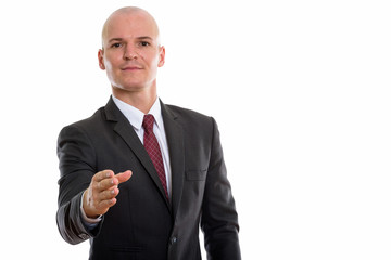 Studio shot of young handsome bald businessman giving handshake