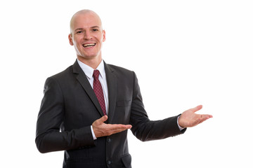 Studio shot of young happy bald businessman smiling while showin