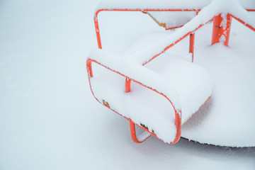playground covered by snow. winter season. child carousel close up