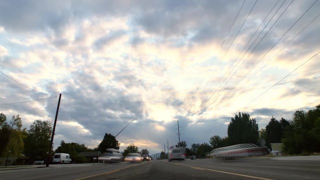 Beautiful time lapse of the morning sunrise as the clouds cross the blue skies. Taken from a suburban road with traffic passing by both ways.