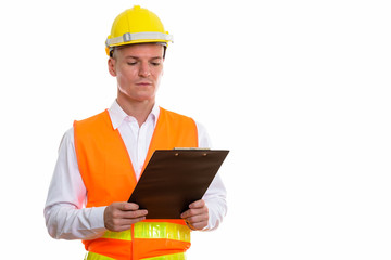 Studio shot of young handsome man construction worker reading on
