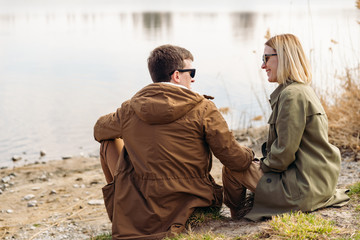 cute couple kissing at riverside sitting on the ground