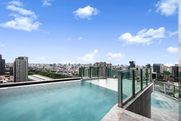 Fototapeta na wymiar Modern luxury swimming pool with city and sky view on top of condominium building.