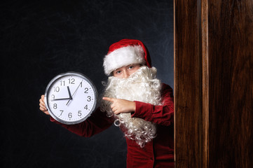 Portrait of a boy in a Santa hat with a clock indicating the time