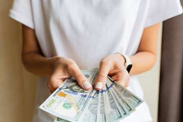 Businesswoman got cash money. Richness and wellbeing concept. Woman hands holding one hundred dollar bills. Woman in white shirt holds pile of dollar banknotes on beige background. Easy cash loans.