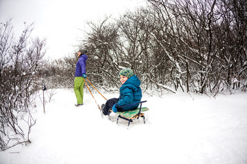 A woman rolls a boy on a sled.