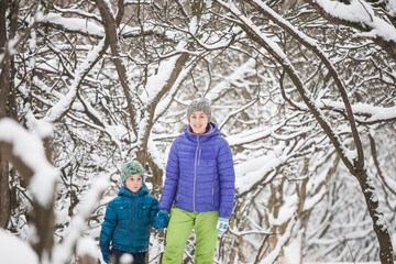 Woman walks with her son over the snow covered forest.