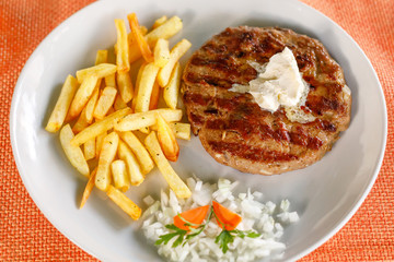 Traditional serbian pljeskavica served with potatoes fries, closeup