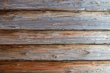 A fragment of a log wall, horizontally placed old logs with traces of twigs and cracks with dried gray moss used as a gasket between the crevices. Wood texture, wallpaper, natural background.
