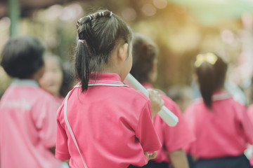 Back view of little girls use paper rolls instead of long cheerleader Baton Sticks for school parade marching practice.