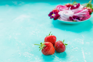 Meringue on pink paper textured background. The concept of the celebration. Valentine's day gift. Selective focus, copy space marshmallow, fluffy dessert zephyr, pink swirl meringue and strawberry.