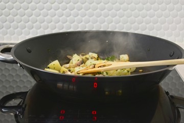 Cooking roast potatoes in a modern kitchen. Focus on spatula.