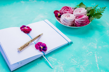 Flat lay with open book with empty pages,and pink meringues on concrete background. Overhead view, copy space. Blogger workplace.Sweet memories.Planning for future. Important thoughts.