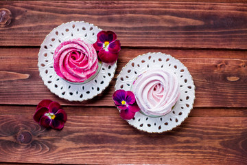 Colorful zephyr on wooden background.Set of homemade white and pink zephyr or marshmallow on wooden background. Marshmallow, Meringue, Zephyr, pansy.Tasty meringues.Copy space