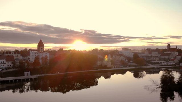 Aerial footage on the pond in the middle of the city, historic town in Poland, recreational path around the lake in the city, ancient buildings of the city, beautiful sunset in Warmia and Mazury