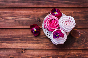Colorful zephyr on wooden background.Set of homemade white and pink zephyr or marshmallow on wooden background. Marshmallow, Meringue, Zephyr, pansy.Tasty meringues.Copy space
