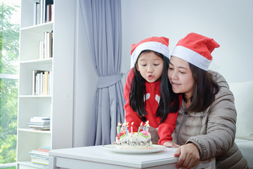 Mother and daughter blowing a birthday cake on Christmas. New year festival concept
