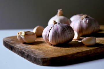 Garlic is placed on an old wooden chopping board, light on one side is not very bright.