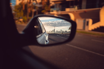 The Perth city skyline in the sideview mirror of a car. Beautiful and quiet sunrise over the city...