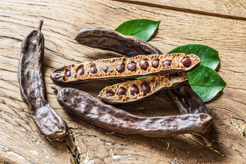 Carob pods and carob beans on the wooden table.
