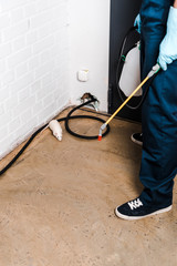 cropped view of exterminator standing near brick wall and rat