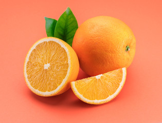 Orange fruit with orange slices and leaves isolated on orange background.