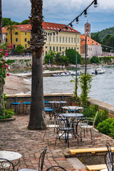 An empty beach bar terrace after rain with a view of the port with sailing boats and the old town, picturesque scene, Vis island, Croatia, Europe. Summer travel