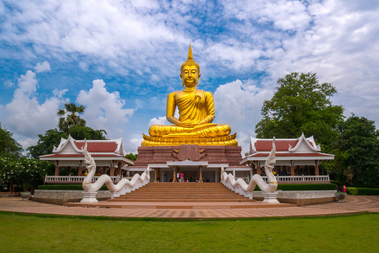 Beautiful  Big Golden Buddha statue against blue sky in Thailand temple,khueang nai District, Ubon Ratchathani province, Thailand.Amazing Buddha image with sunny sky clouds.