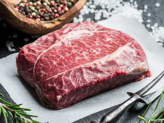 The top blade steak or beef steak on the graphite board with herbs and spices.