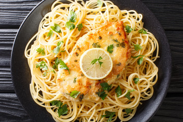 cooked chicken Francaise with spaghetti in lemon wine gravy close-up on a plate. Horizontal top view