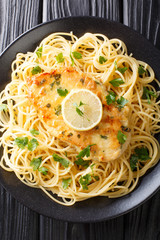 Chicken Francaise (or Chicken Francese) is an Italian-American dish served with spaghetti with lemon sauce close-up on a plate. Vertical top view