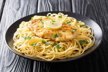 Roasted breaded chicken Francaise with a side dish of spaghetti close-up on a plate. Horizontal