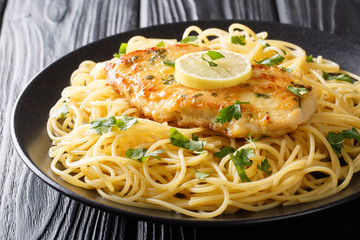 Tasty classic chicken Francaise with spaghetti in lemon wine sauce close-up on a plate. horizontal