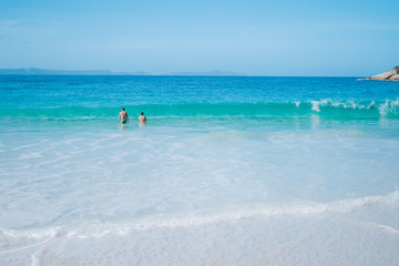 Fototapeta na wymiar Two boys swimming in the vibrant blue ocean water of Albany, Australia. 