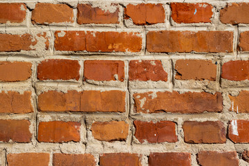 Obraz premium Rough rough red brick wall close-up. Texture of a red wall with a cement seam.
