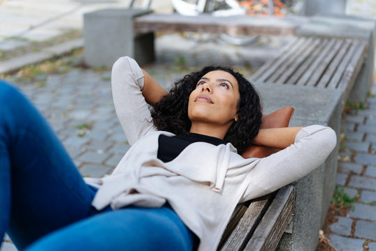 Young woman lying on a bench in an urban park
