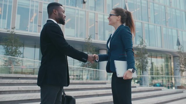 Business partners handshake Business people meet and shake hands in front of office center. Handshake between colleagues man and woman. Casual formal business clothing, young startuppers
