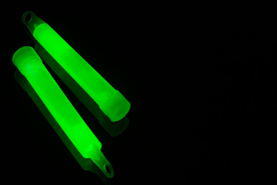 techno party gear and nightclub conceptual idea with vibrant color glow sticks in green glowing in the dark with copy space