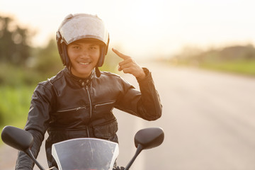 Handsome motorcyclist point the finger to his helmet - obrazy, fototapety, plakaty