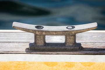 Close up of alloy boat mooring cleat on wooden dock