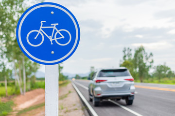 Modern car running on asphalt road / bicycle lane and tread on white bicycle sign