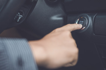 Hand of man pressing button start/stop car engine inside the modern car