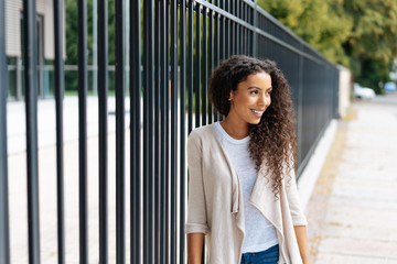 Relaxed attractive woman leaning on an urban fence