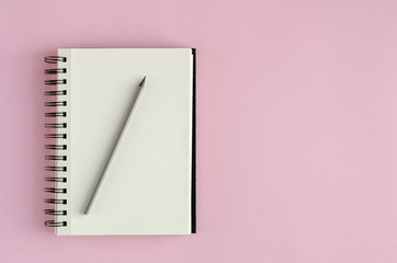 Note pad with pencil composition on pink background.