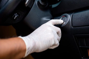 Hand wearing white gloves and pushing button start/stop car engine