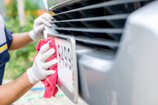 Man Using Red Cloth To Cleaning Front Car Plate Number