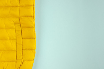 Yellow kids winter jacket composition on blue background.