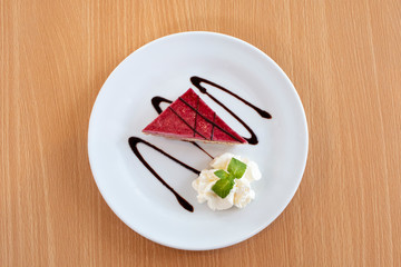 Delicious piece of strawberry cake  with chocolate sauce on white plates, top view on table wooden.