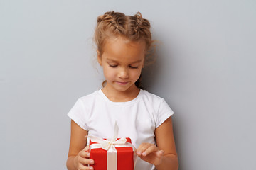 Nice little girl holding a red gift box in her hands