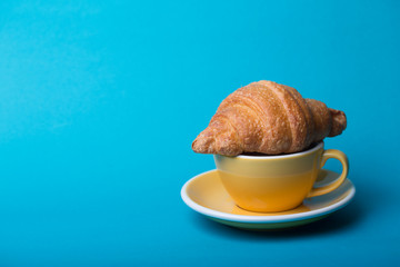 yellow cup with croissant on a blue background